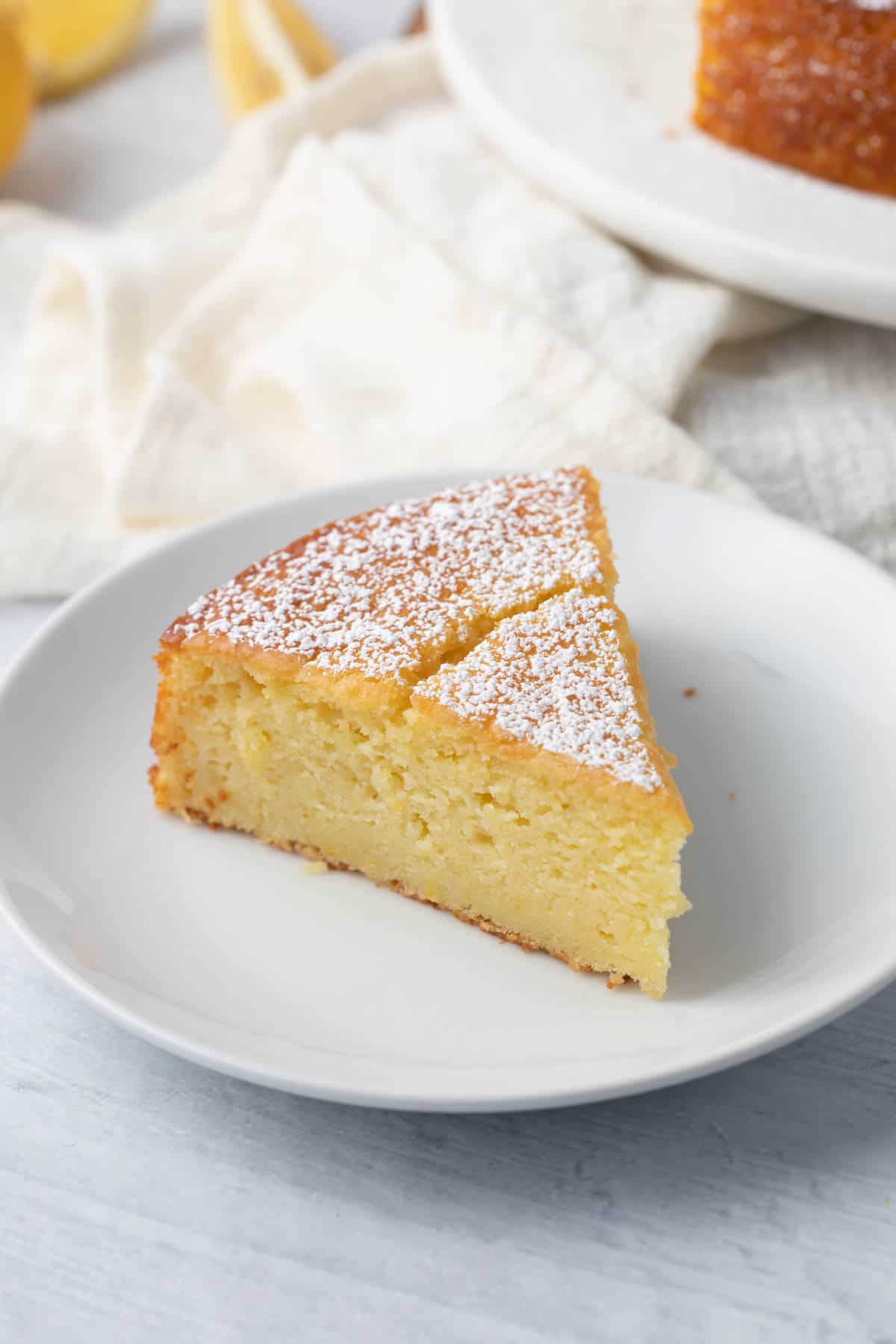Slice of lemon ricotta cake showing a rich and moist crumb, topped with powder sugar.