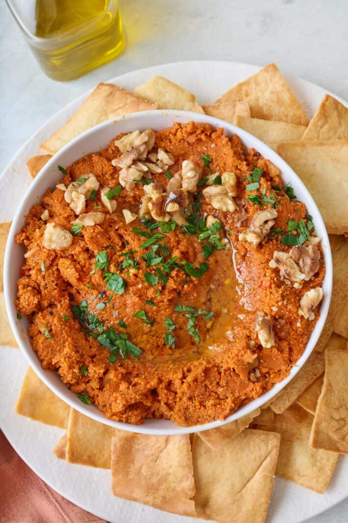 Close up shot of muhammara with a spoon inside the dip