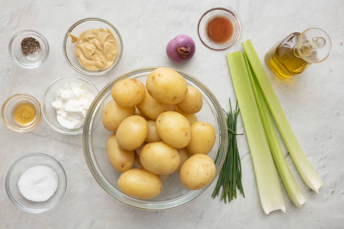 Ingredients for recipe: pepper, honey, salt, greek yogurt, mustard, baby potatoes, shallot, chives, celery stalks, red wine vineagar, and oil.