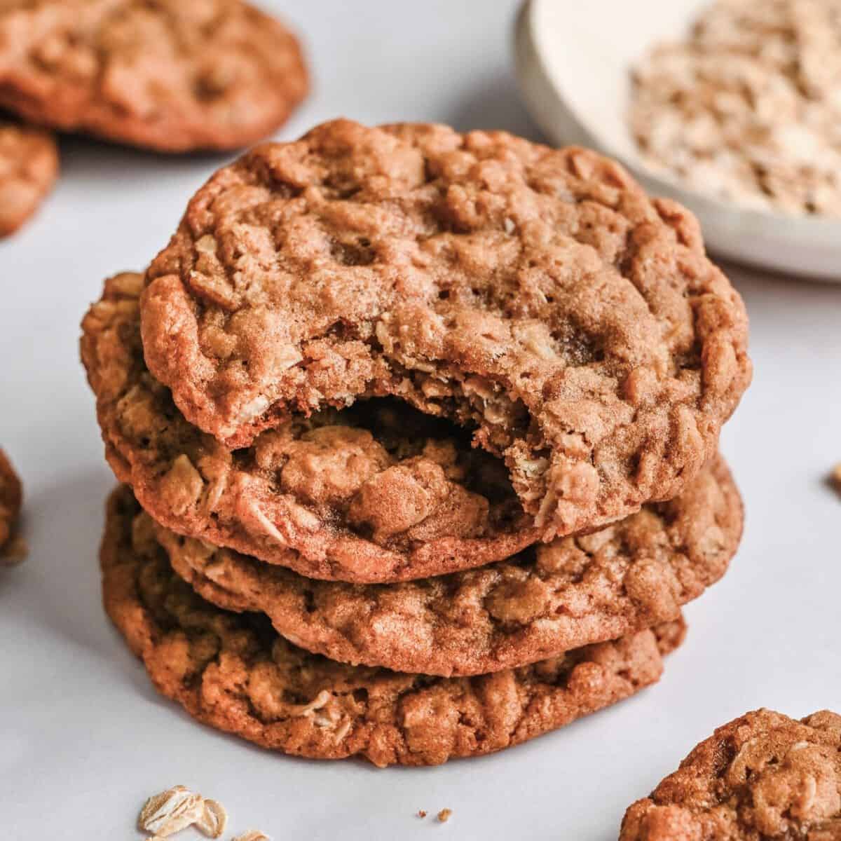 Oatmeal cookies stacked up with one having a bite taken out.