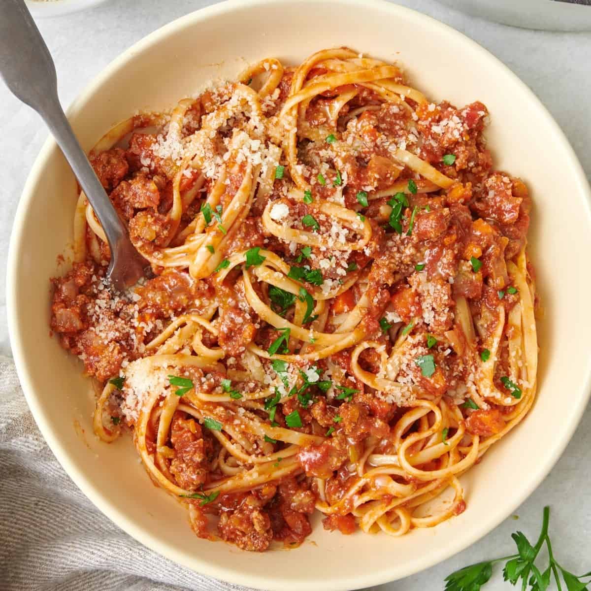 Pasta Bolognese in a large pan with a wooden spoon