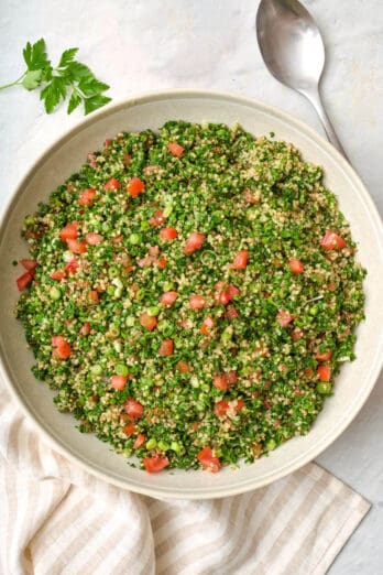 Quinoa tabbouleh in a large serving bowl with a spoon nearby.