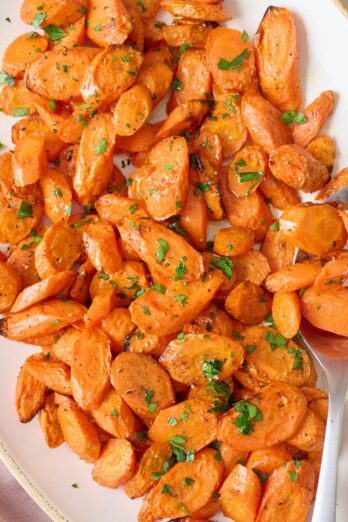 Platter of oven roasted carrots sprinkled with parsley.