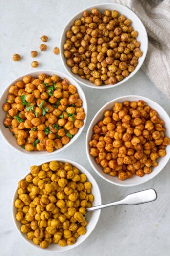 Roasted chickpeas seasoned four different ways, each in a separate small bowl.