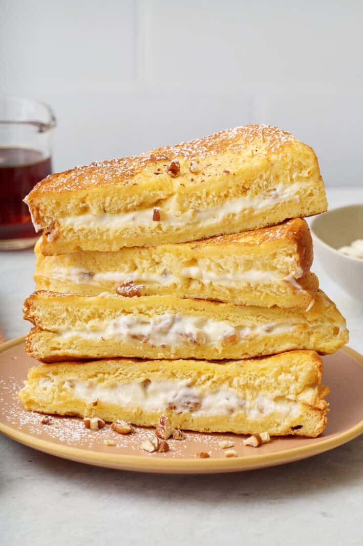 Stuffed french toast halves stacked up 4 tall to show the cream cheese and pecan filling.