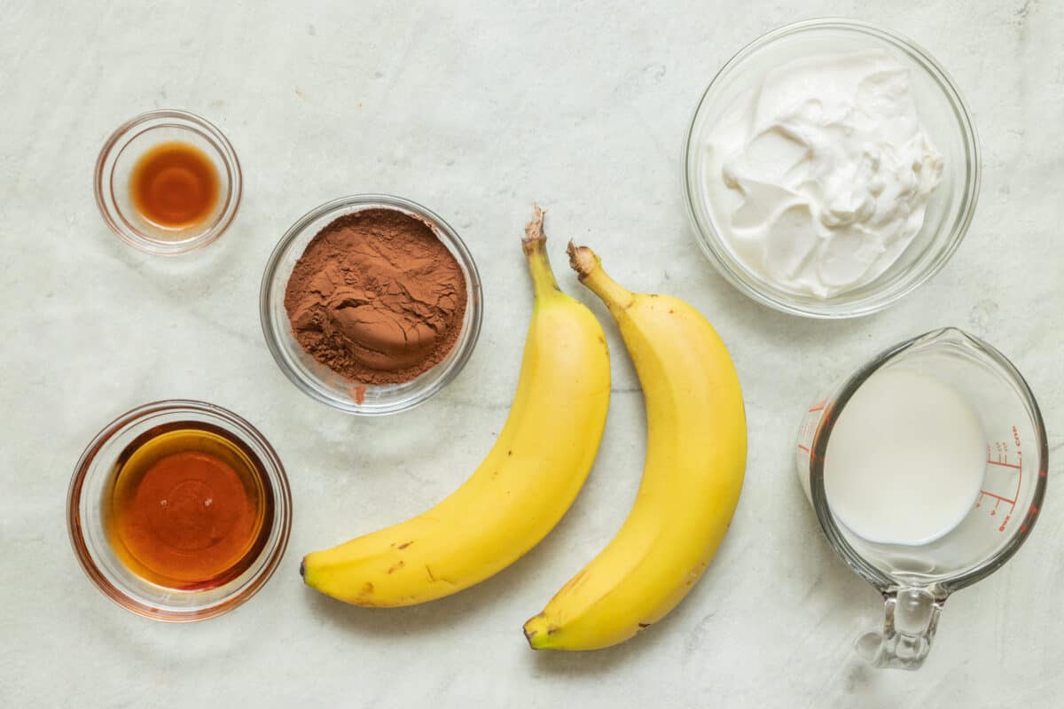 Ingredients for recipe: vanilla, maple syrup, bananas, cocoa powder yogurt, and milk.