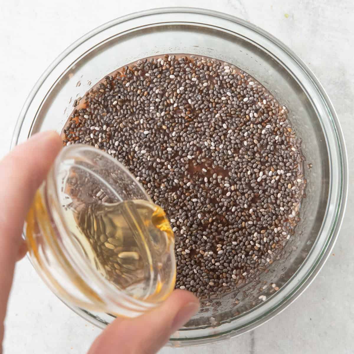 Honey being drizzled into the jar from above using measuring spoon.
