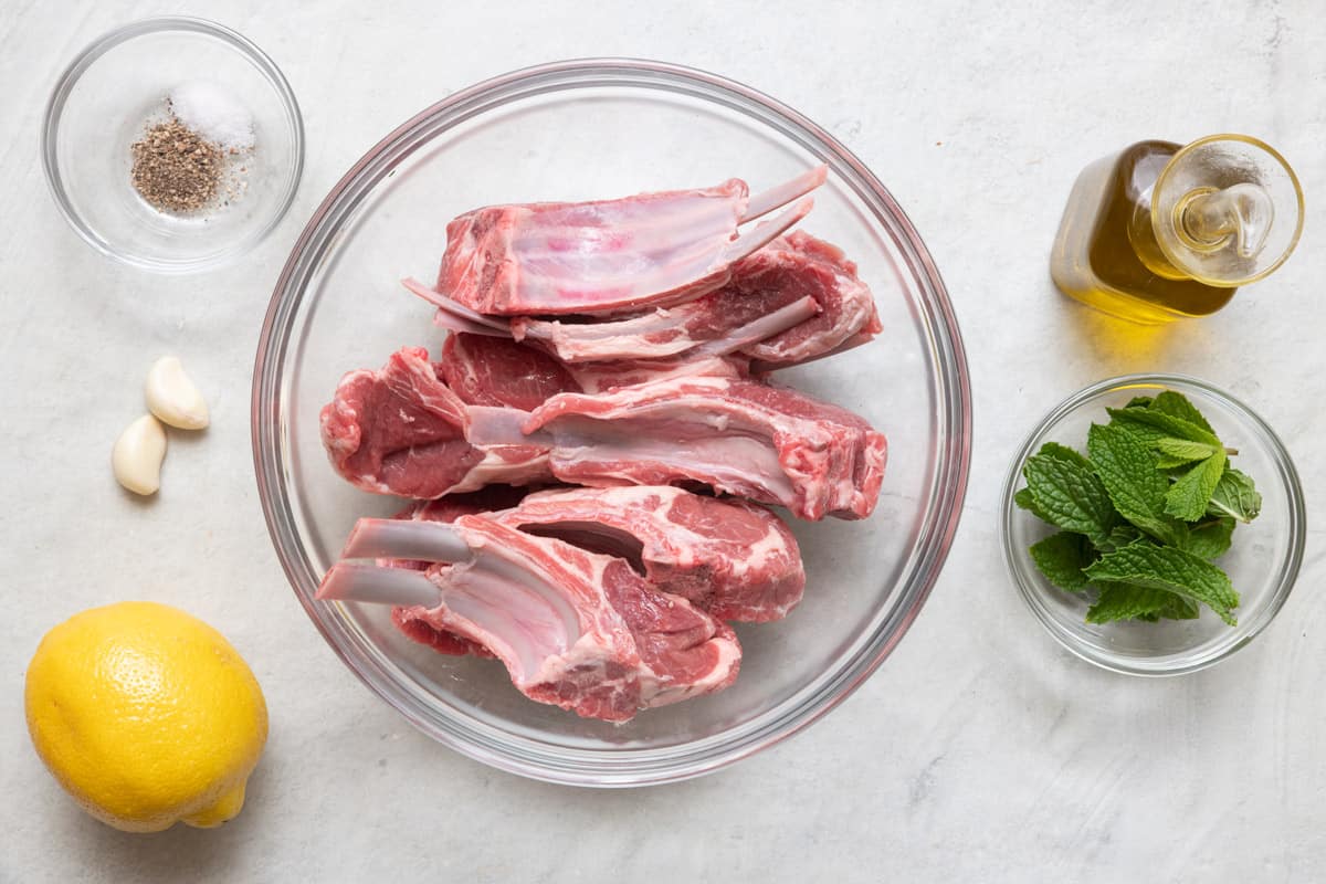 Ingredients for recipe: raw lamb chops, salt and pepper, garlic, lemon, oil, and mint.