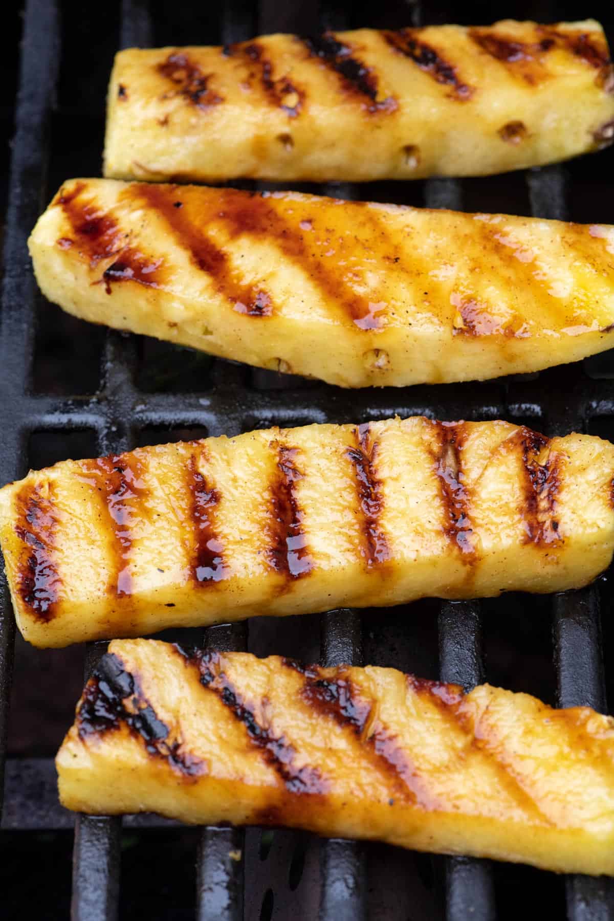 Pineapple spears on a grill with caramelized grill marks.