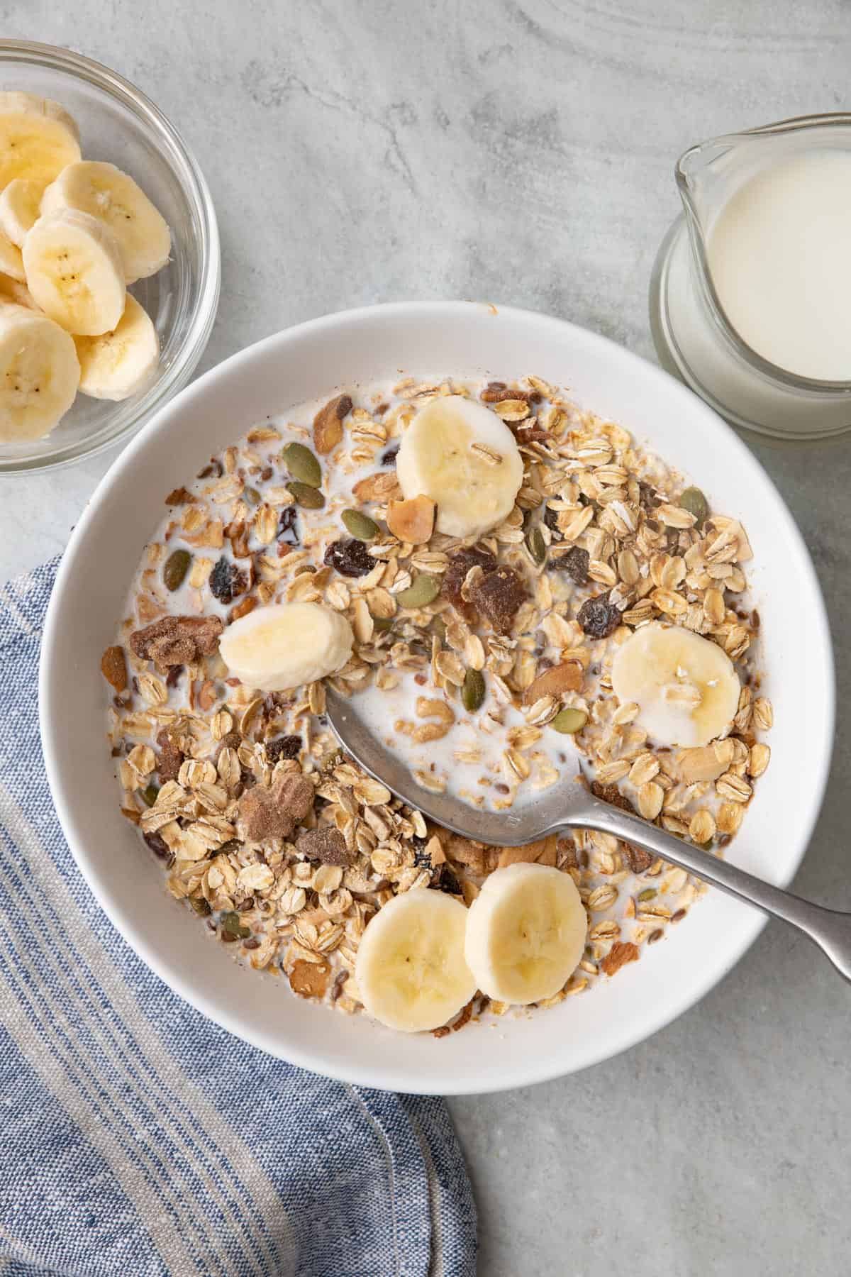 A bowl of muesli served cold with milk and bananas.
