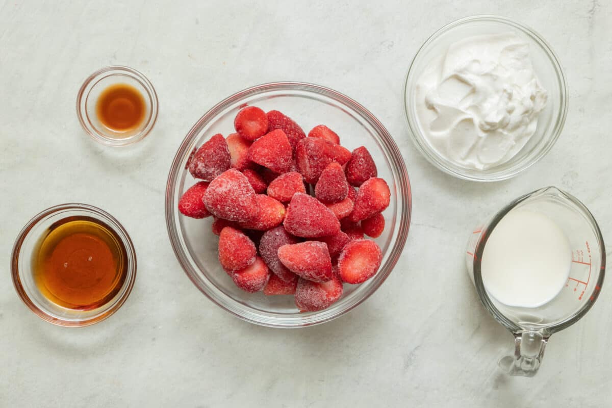 Ingredients for recipe: vanilla, maple syrup, frozen strawberries, yogurt, and milk.