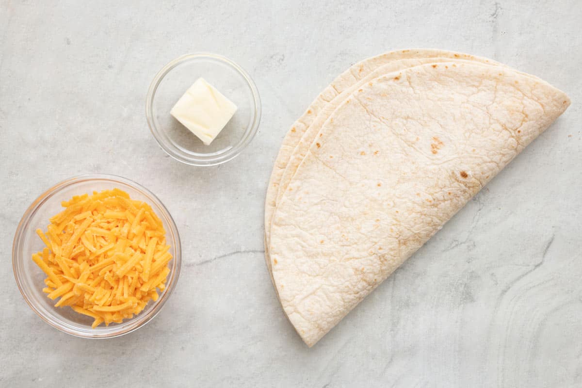 Ingredients for recipe: shredded cheese, butter, and two tortilla shells.