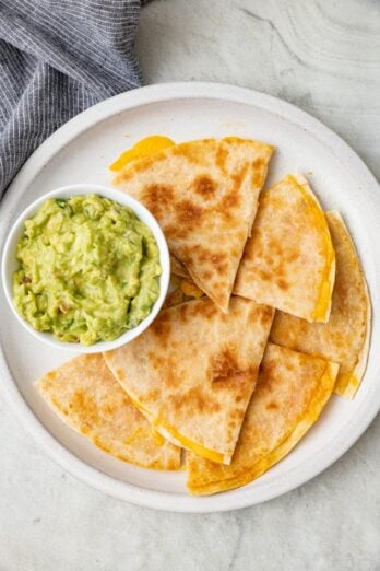 Quesadilla slices on a plate with a side of guacamole.