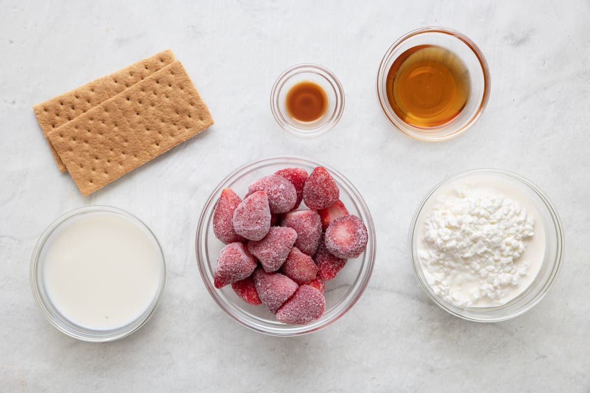 Ingredients for recipe before prepping: 2 graham crackers, milk, vanilla, frozen strawberries, maple syrup, and cottage cheese.