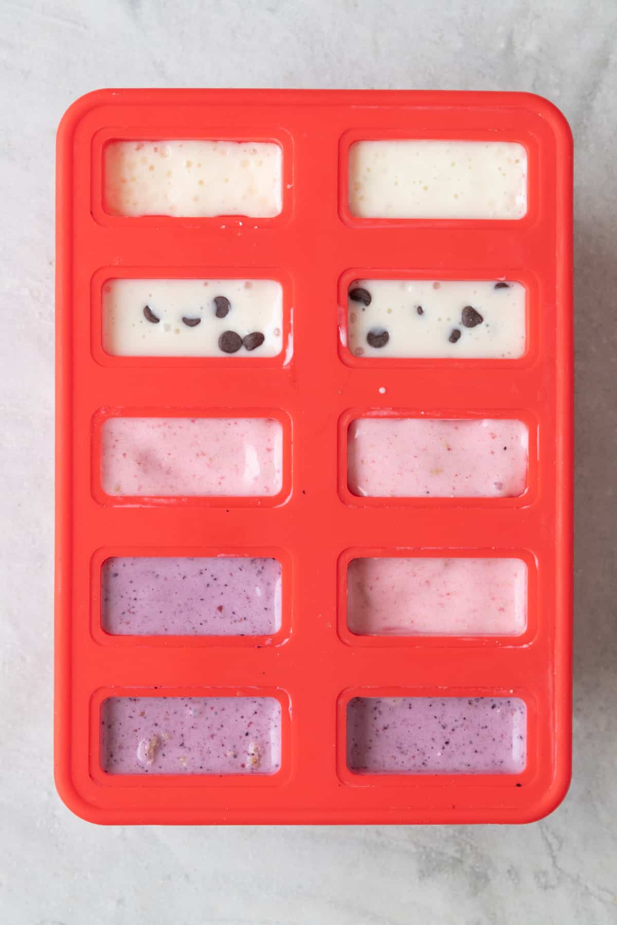 Four different flavored cottage cheese ice cream mixture in a silicone popsicle mold.