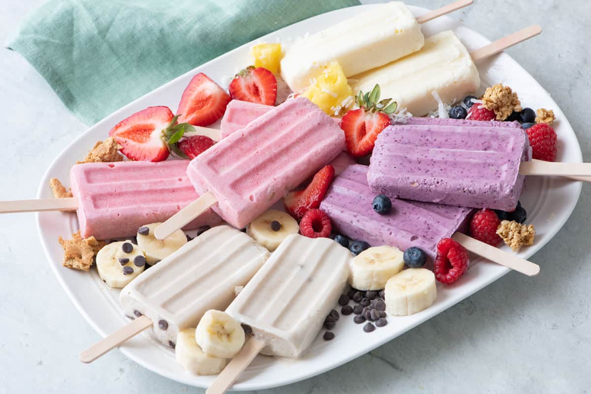 Cottage cheese ice cream popsicles on a tray with fresh and added ingredients.