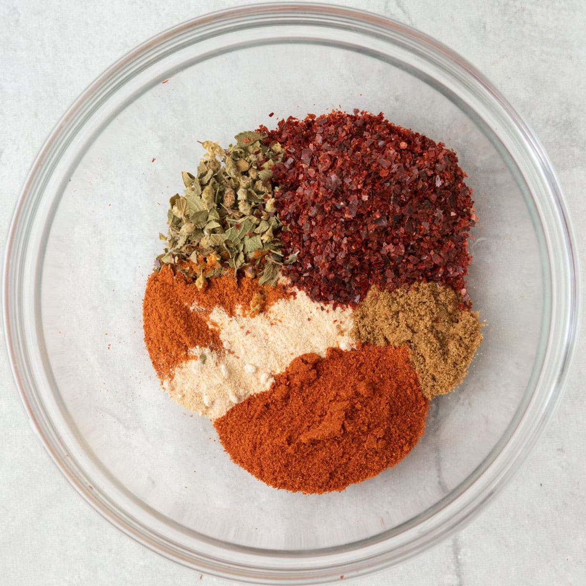Ground chili peppers in a bowl with remaining seasonings added before mixing.