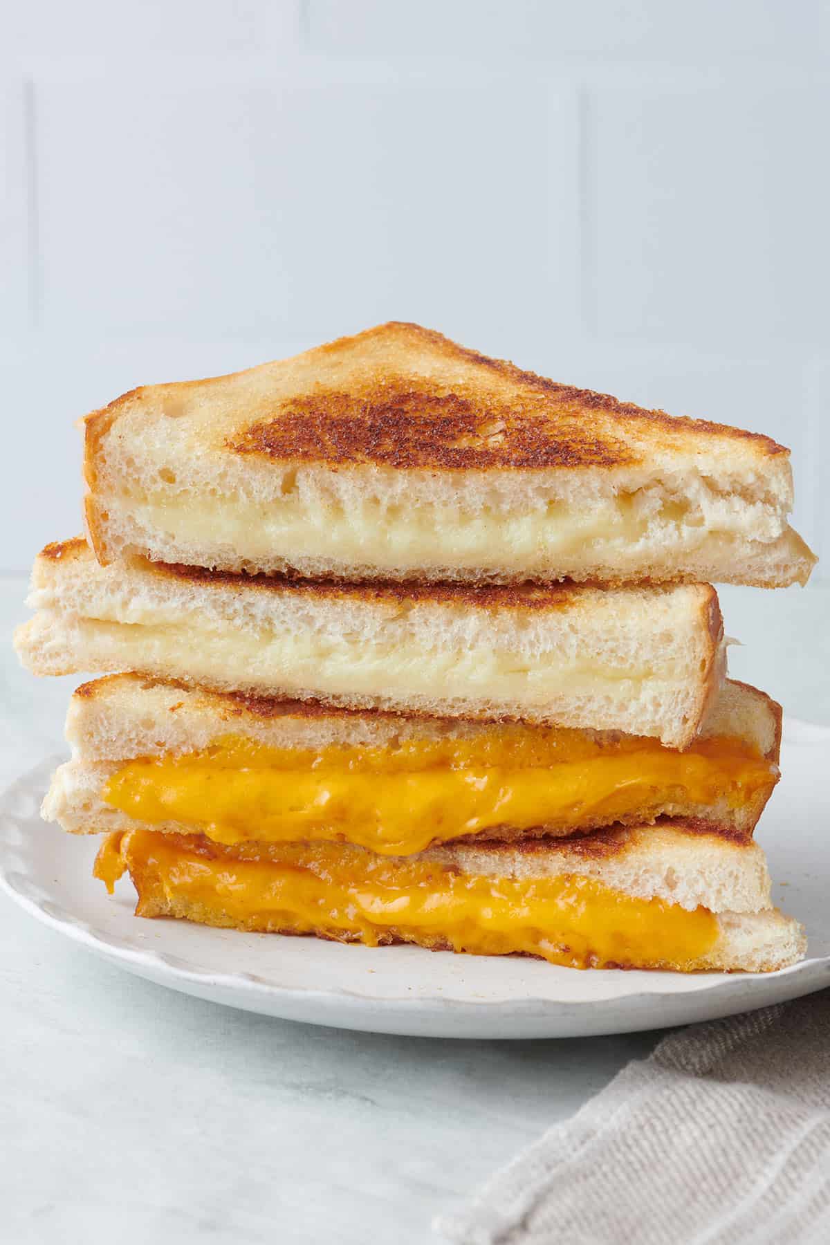 Grilled cheese halves stacked on top of each other on a plate.