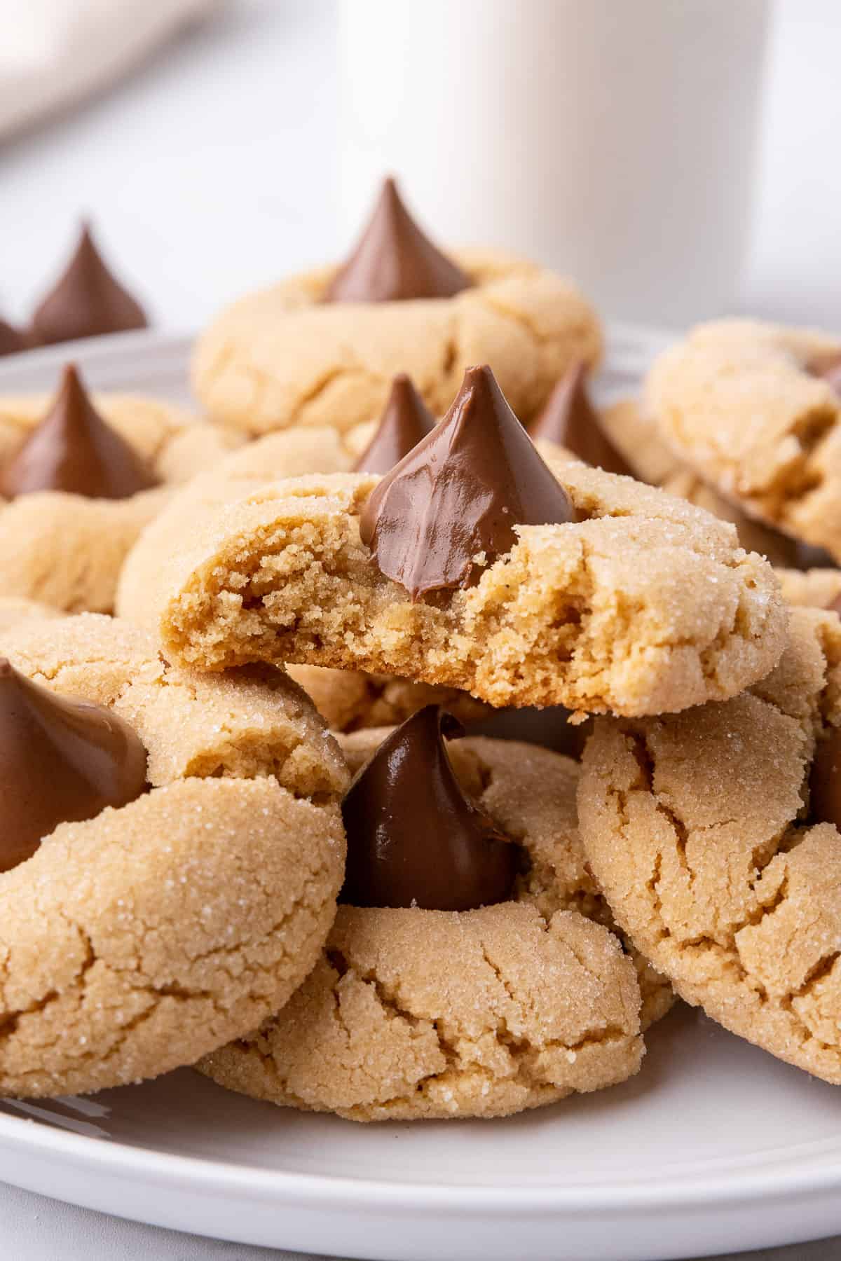 Close up of a plate of peanut butter blossoms with a bite taken out of one.