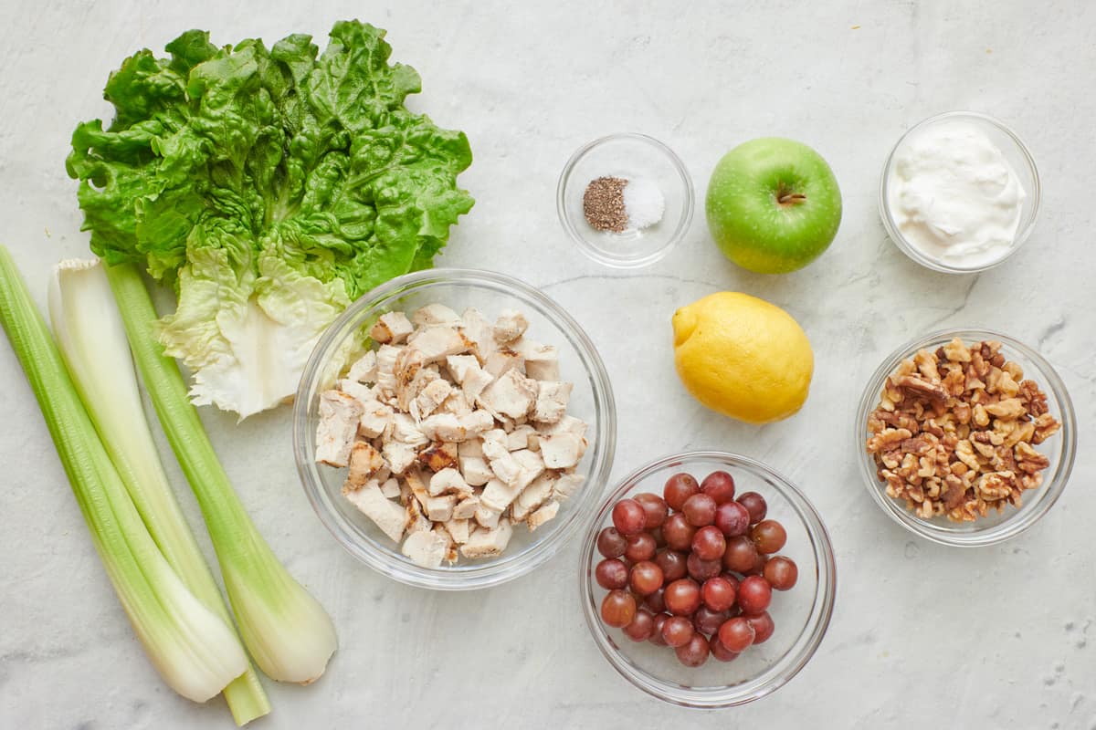 Ingredients for recipe: celery, lettuce, chopped cooked chicken, salt and pepper, apple, lemon, yogurt, grapes, and walnuts.