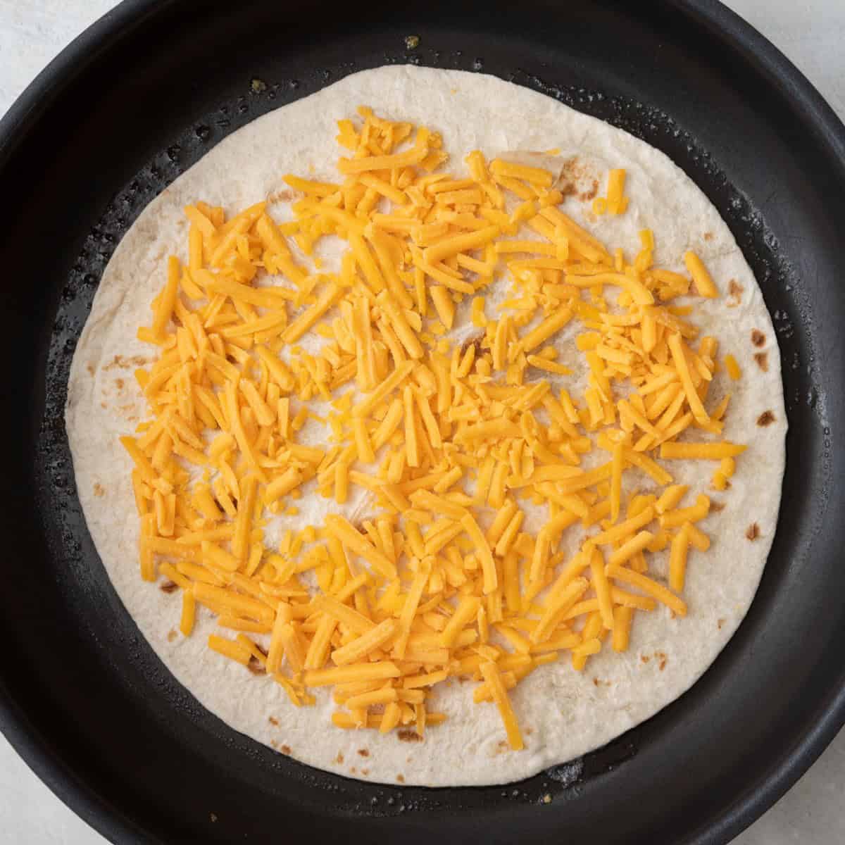 Cheese added on top of tortilla.