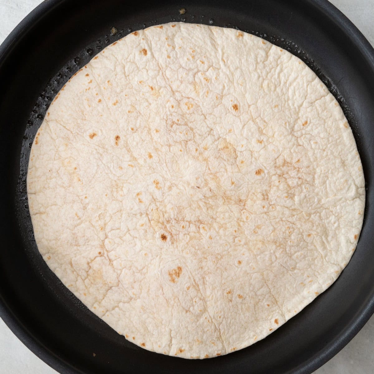 Second tortilla added on top of cheese.