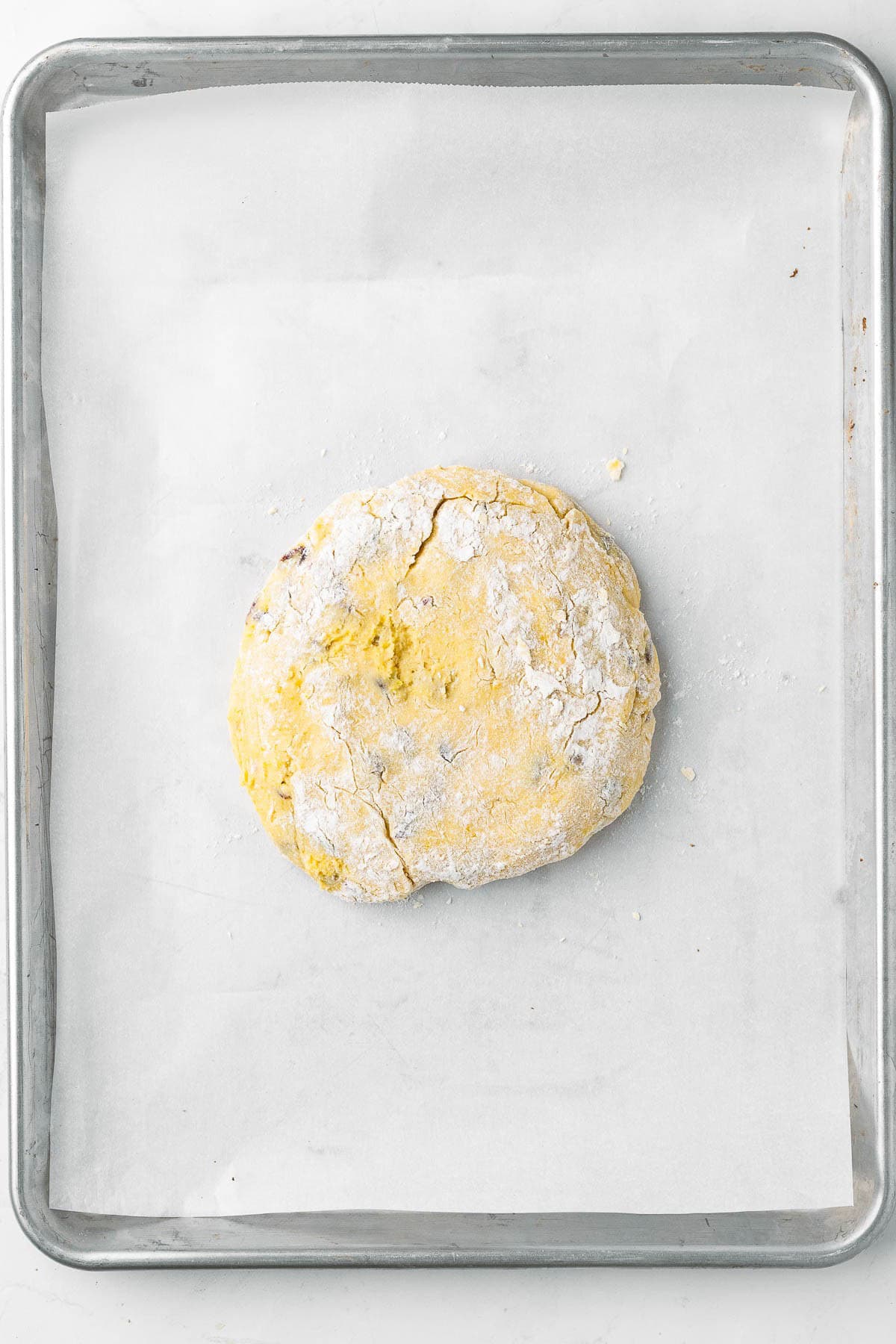 Kneaded dough transferred to parchment paper lined baking sheet before shaped.