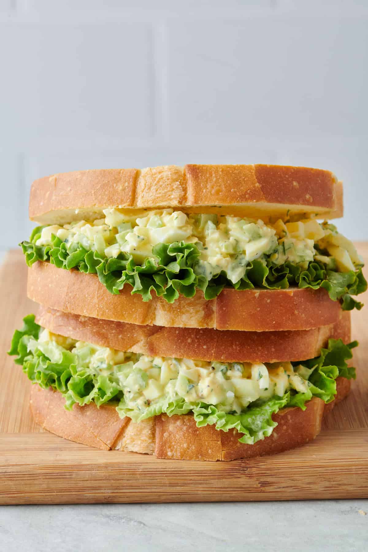 Two egg salad sandwiches stacked on top of each other.