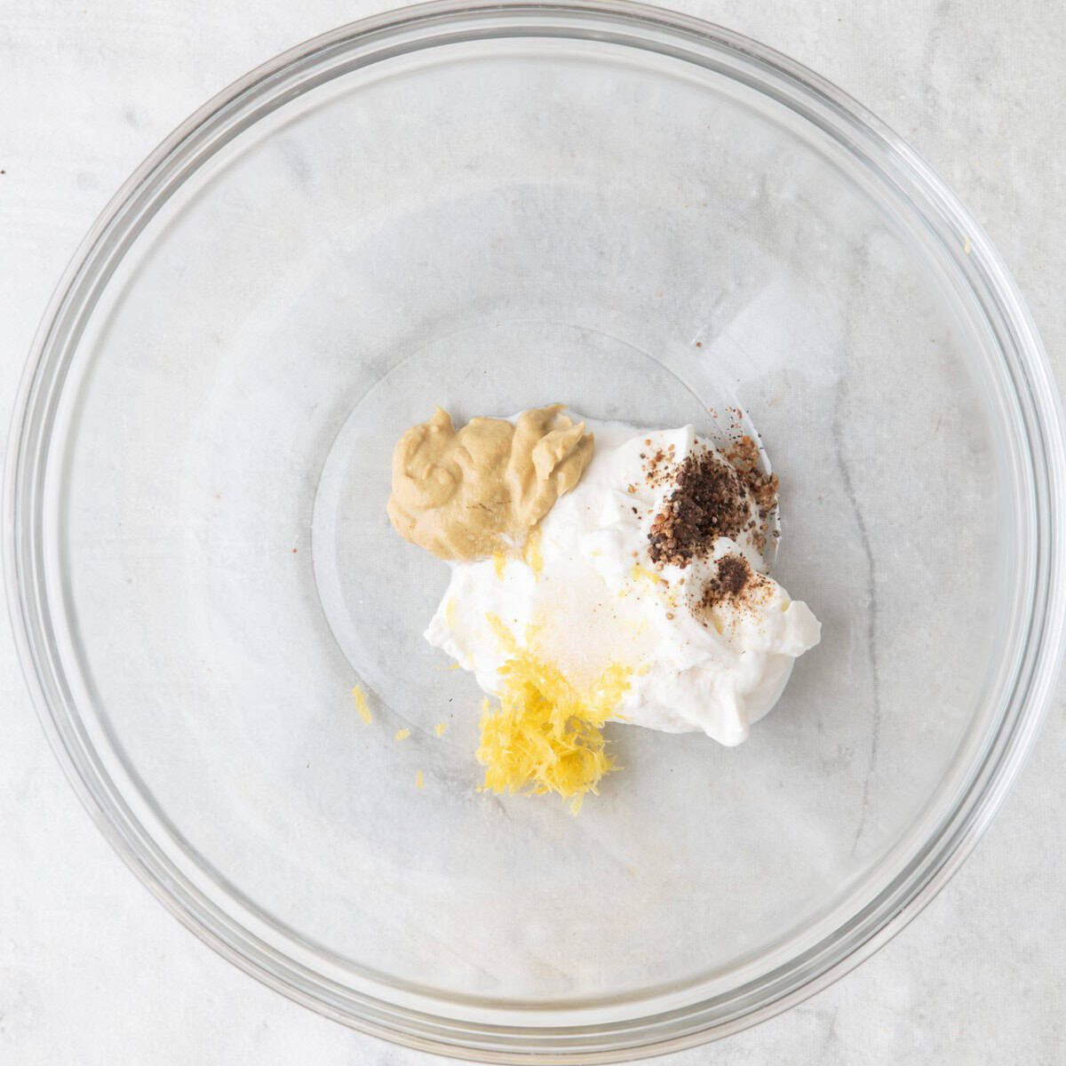 Yogurt, dijon, zest, salt and pepper in a bowl before mixing.