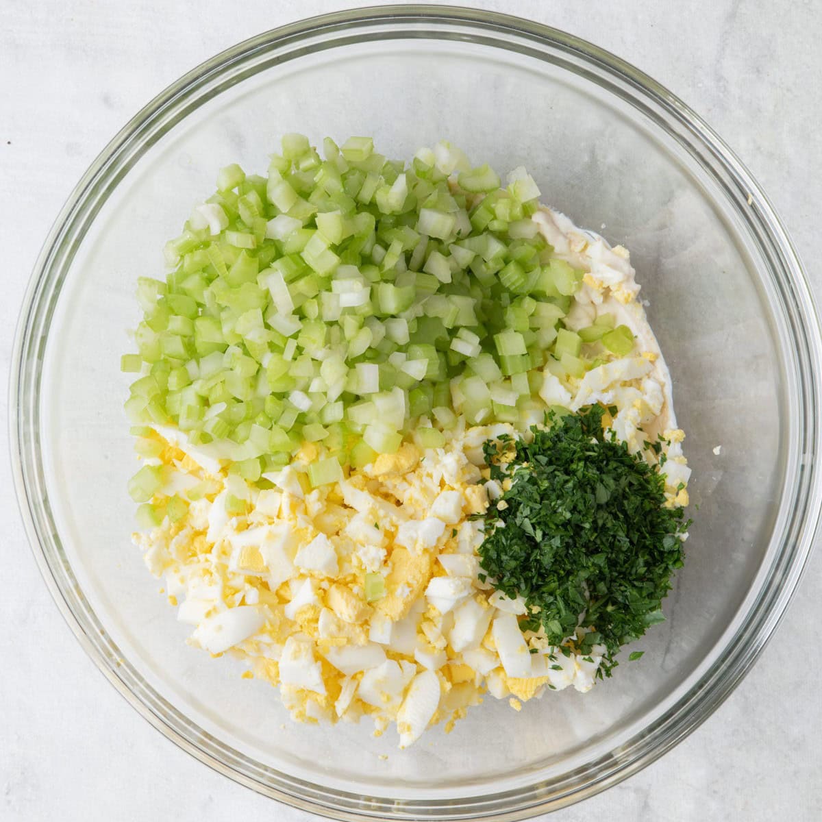Eggs, celery and parsley added on top with celery and parsley added ready to mix into a healthy egg salad.