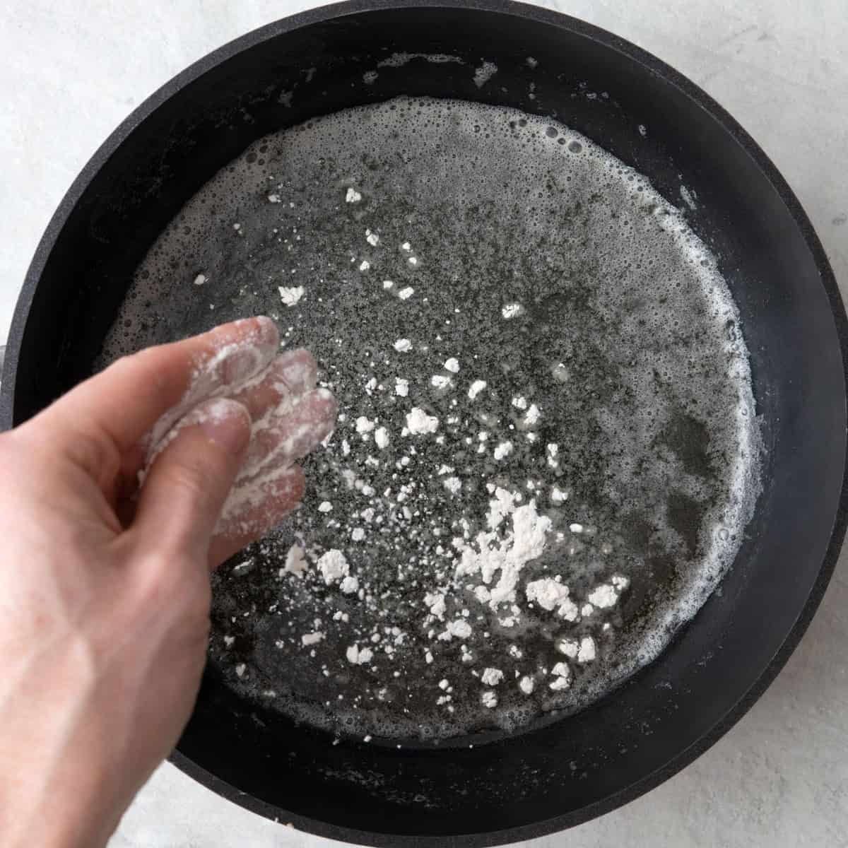 Sprinkling flour over melted butter in a saucepan.