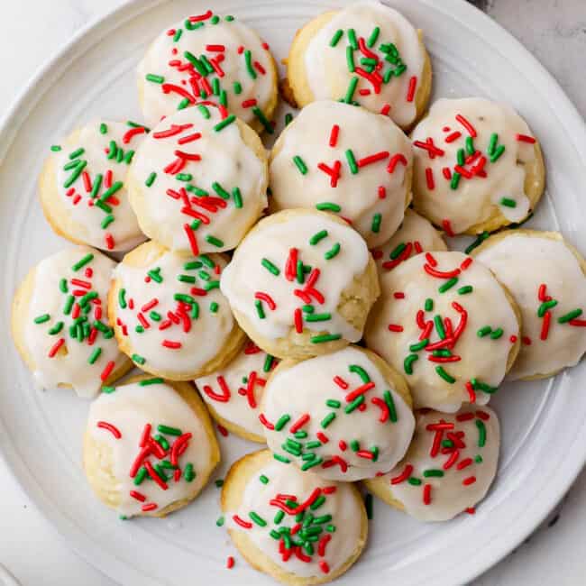 Decorated Italian Christmas cookies stacked on a round plate.