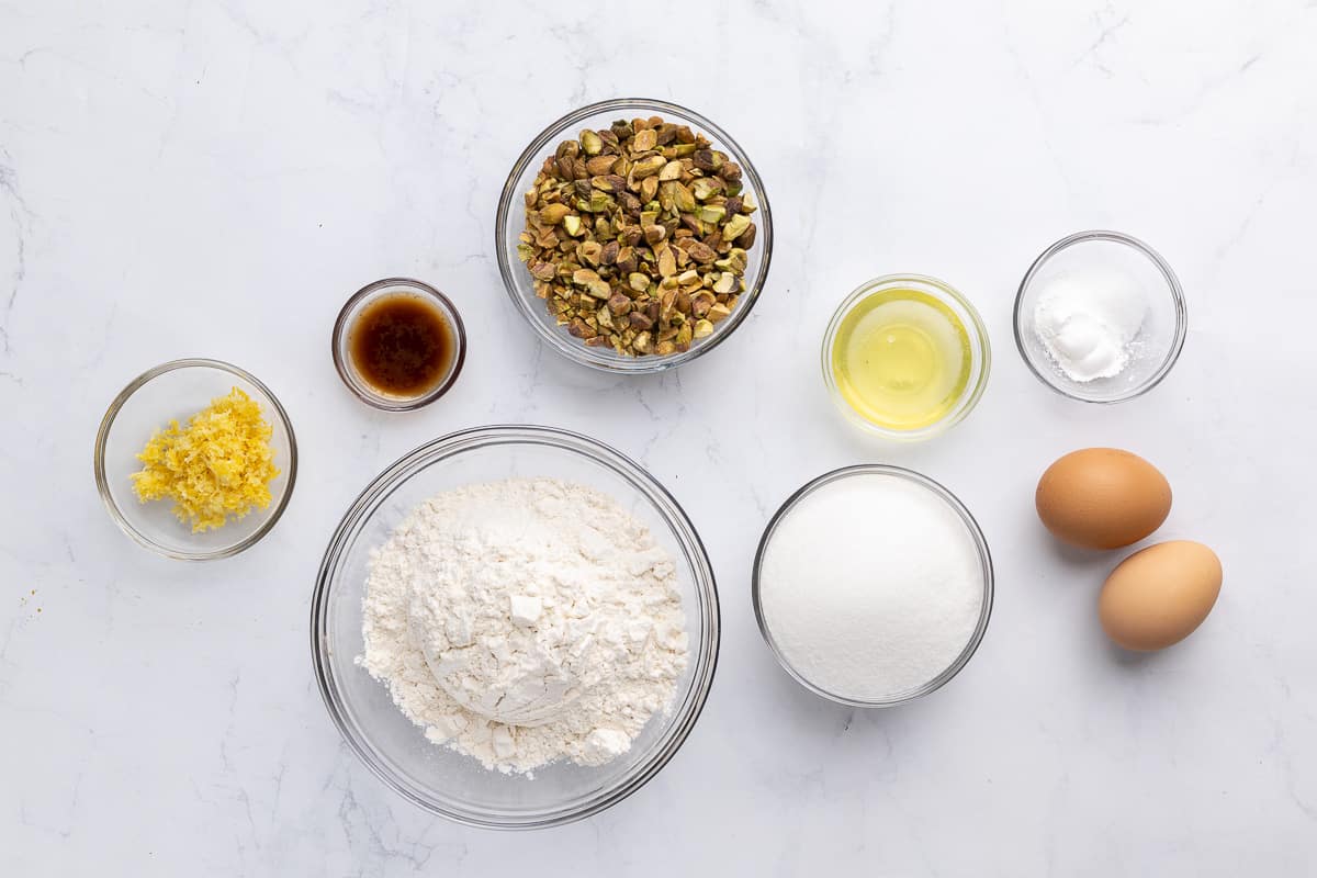 Ingredients before prepping: lemon zest, vanilla, pistachios, flour, sugar, egg white, rising agents, and eggs.