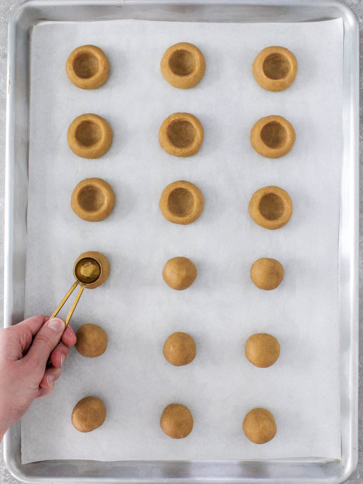 Pressing an indent into cookies with thumb or ½ round teaspoon with a few already prepared.