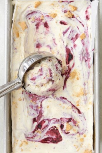 Blueberry swirl ice cream being scooped out with an ice cream scoop after freezing.