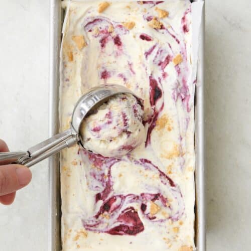 Blueberry swirl ice cream being scooped out with an ice cream scoop after freezing.