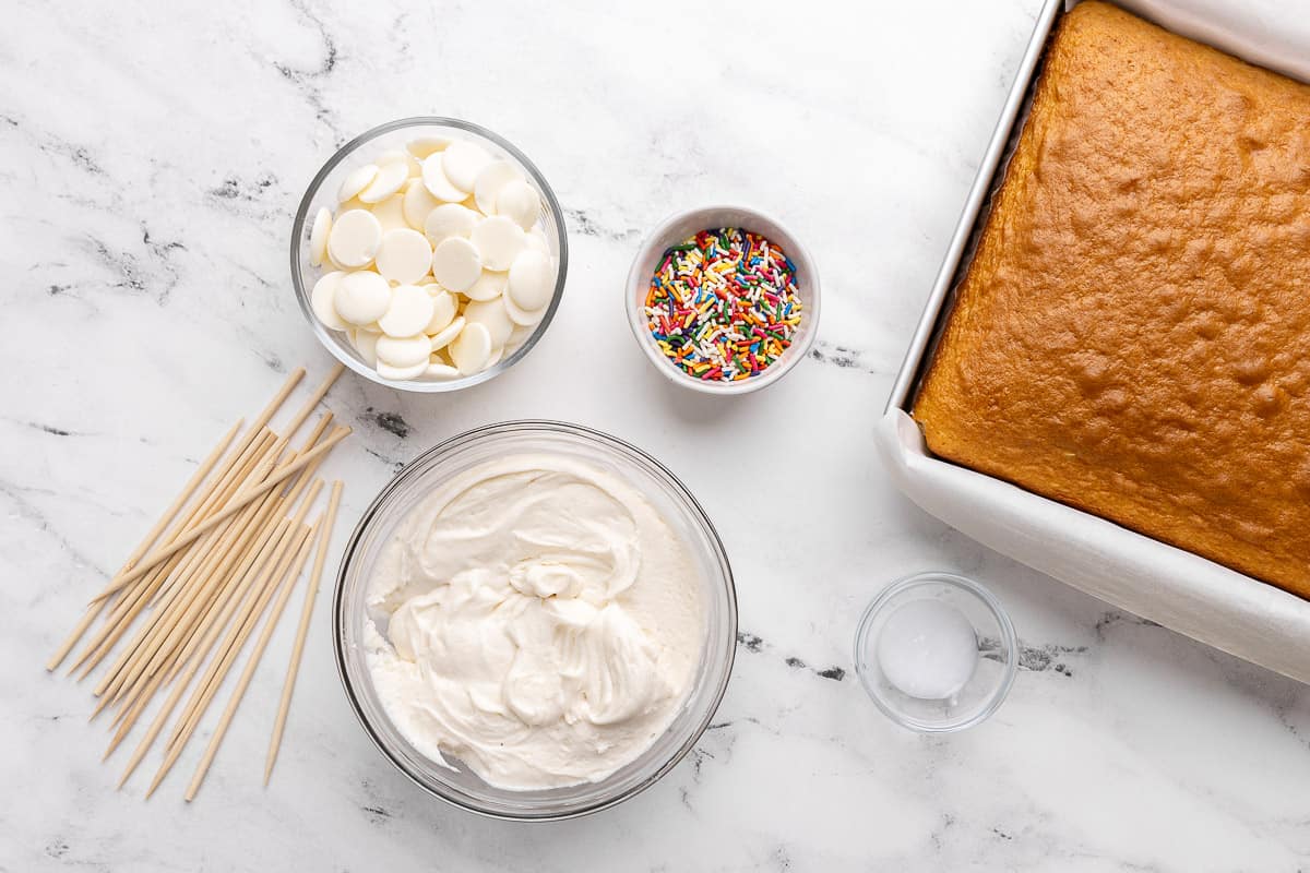 Ingredients for recipe: white chocolate wafers, buttercream frosting, sprinkles, coconut oil, and sticks.