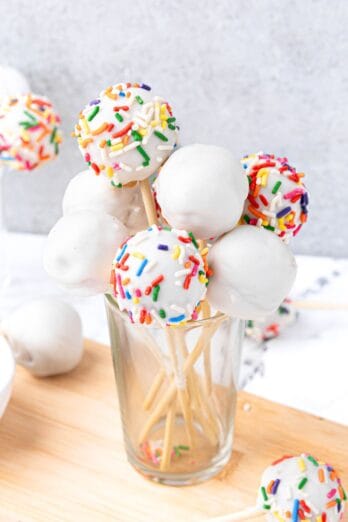 Starbucks copycat cake pops in a glass with more cake pops around. Some decorated with colored sprinkles.