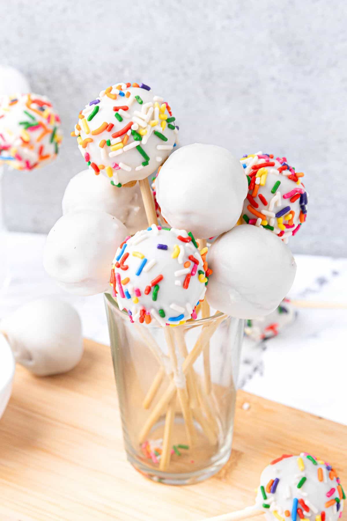 Starbucks copycat cake pops in a glass with more cake pops around. Some decorated with colored sprinkles.