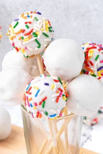 Cake pops in a glass, some decorated with sprinkles.