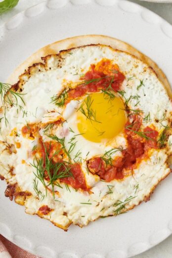 Crispy fried feta eggs with harissa on a tortilla shell garnished with fresh dill.