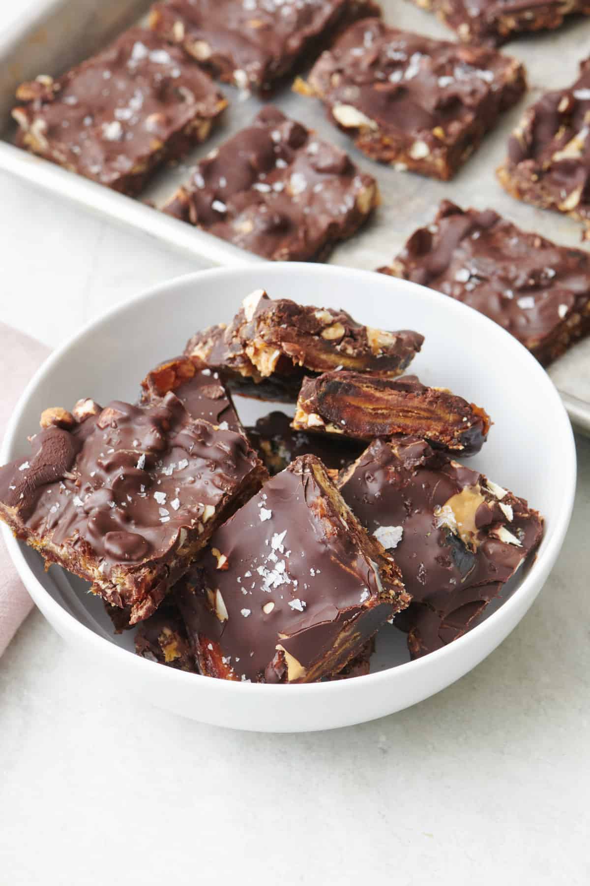 Date bark pieces in a bowl with tray of more nearby.