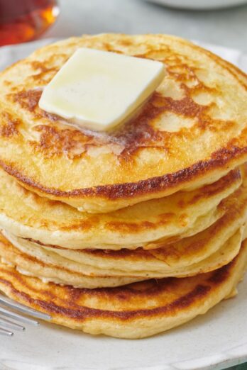 Stack of fluffy greek yogurt pancakes with a pat of butter on top.