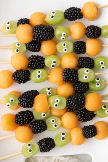 Halloween fruit kabobs on a platter, made with grapes, blackberries, and cantaloup.