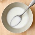 Cornstarch slurry in a bowl with a spoon dipped in.