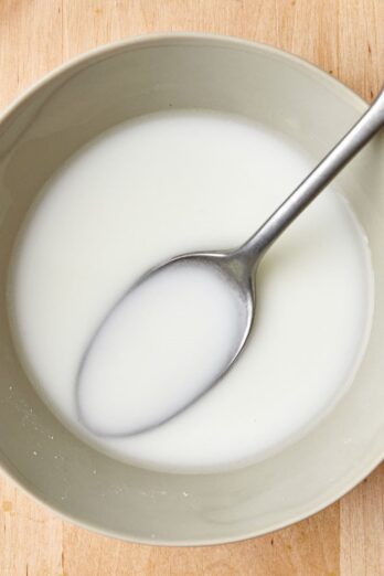 Cornstarch slurry in a bowl with a spoon dipped in.