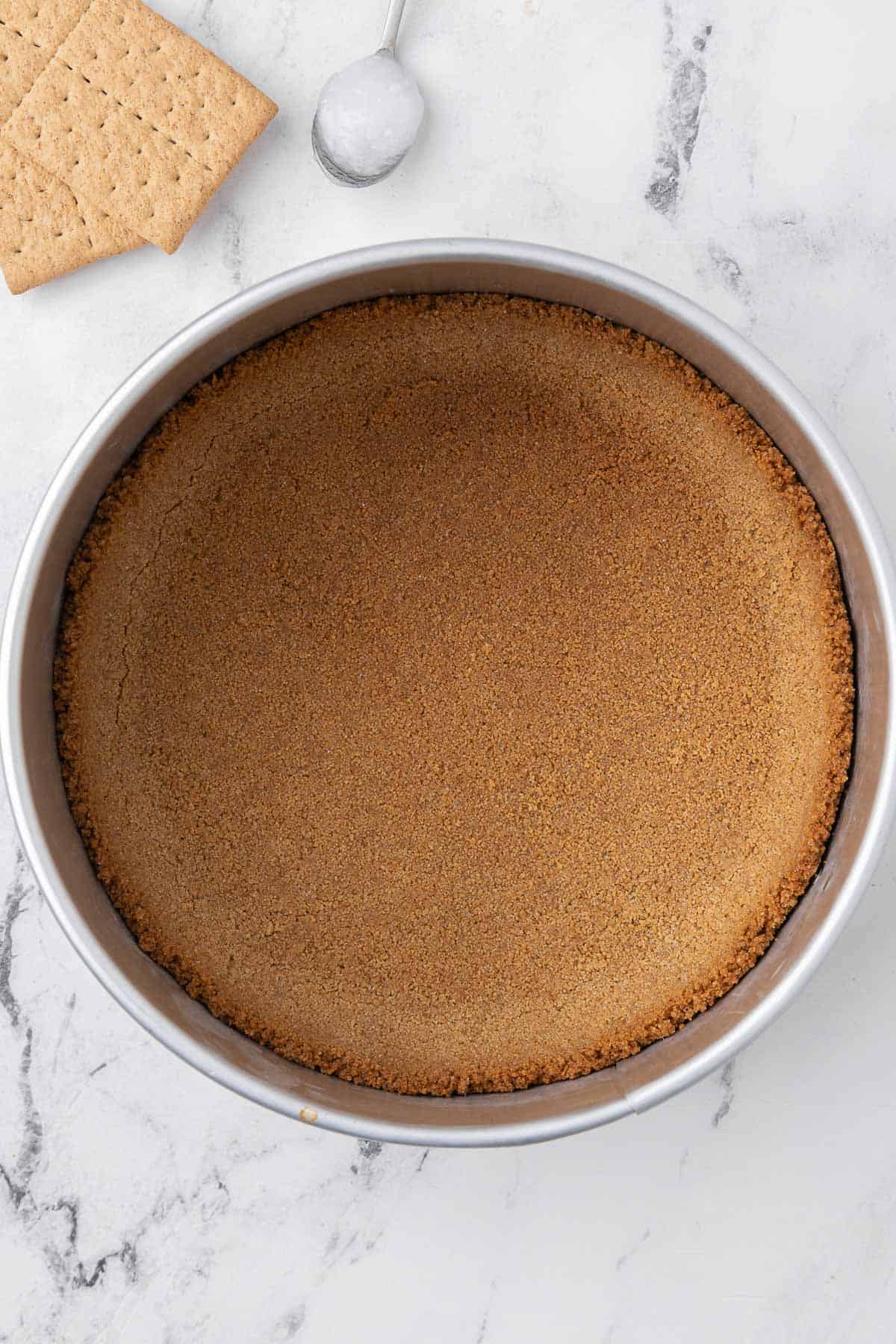 Coconut oil graham crack crust formed and toasted in a spring form pan.