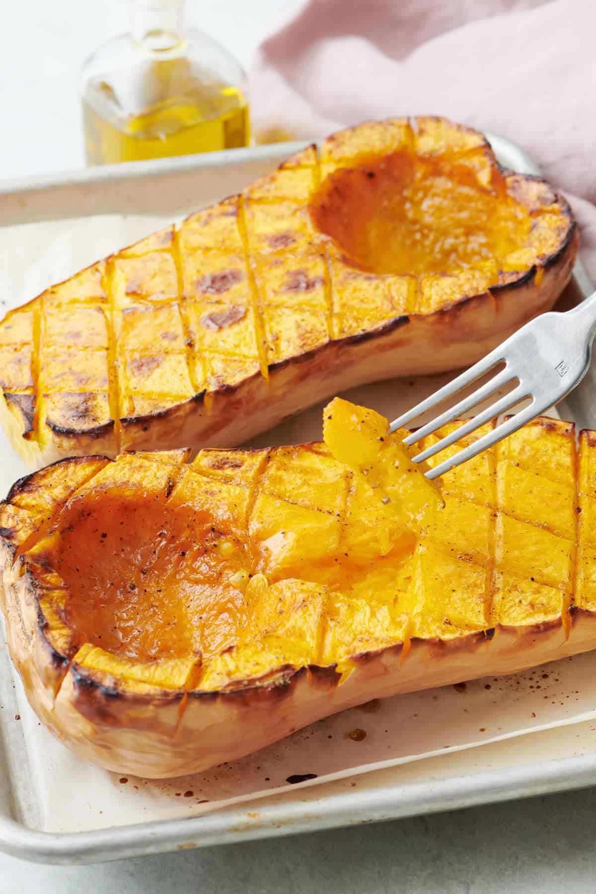 Roasted butternut squash on a baking sheet with a fork lifting up a piece.
