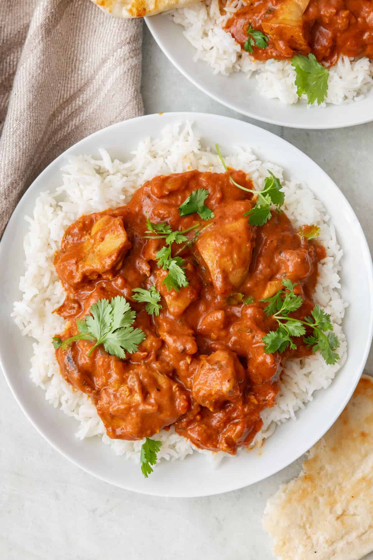 Butter chicken over rice on a plate and garnished with fresh cilantro.