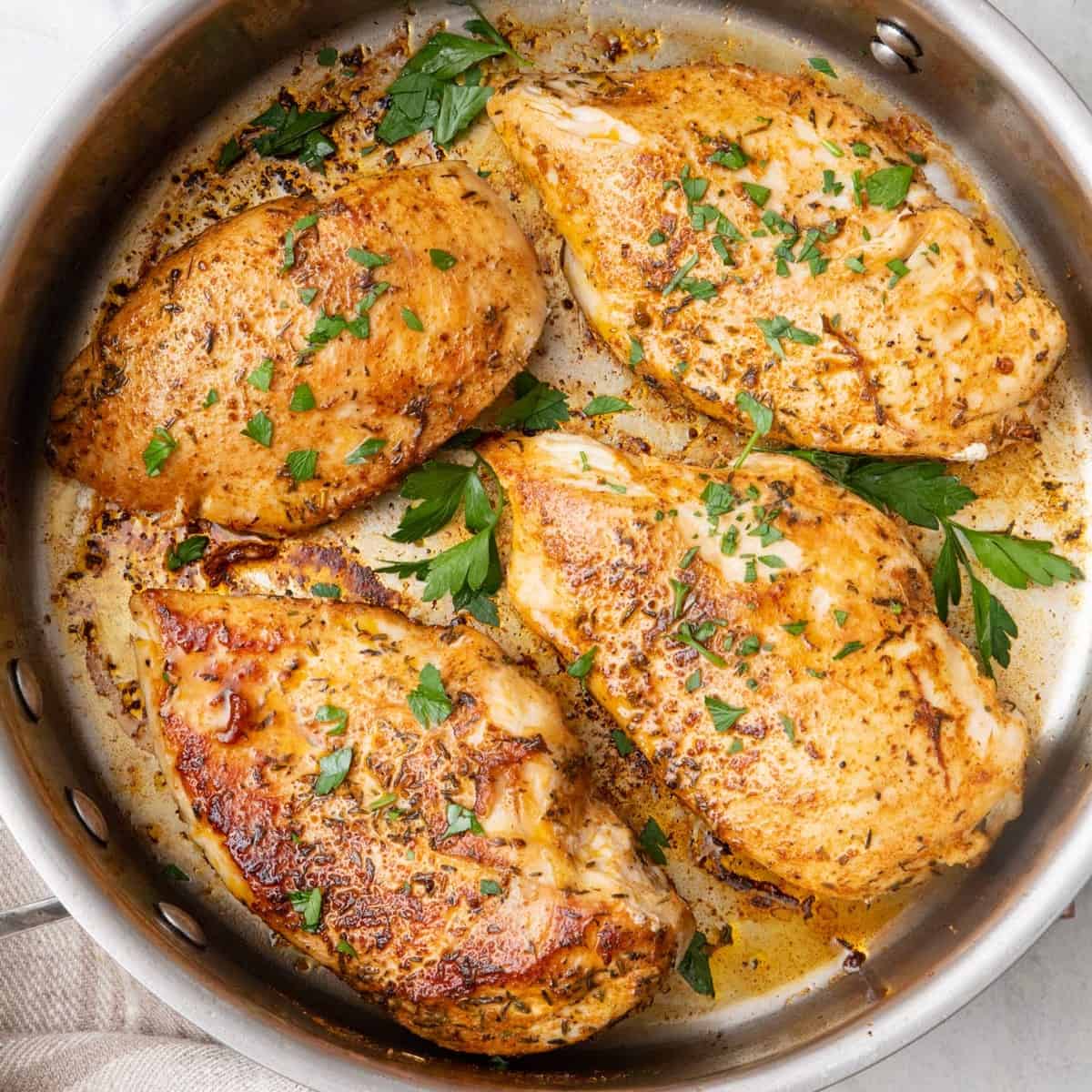Square image of pan seared chicken in pan.